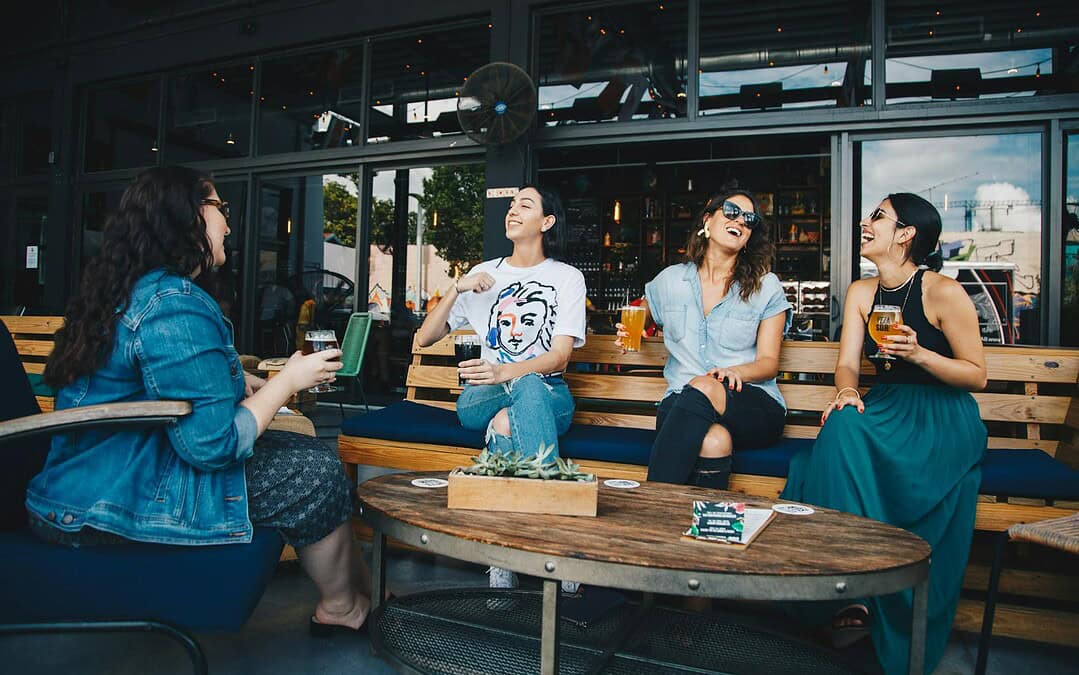 four women chatting while sitting on bench