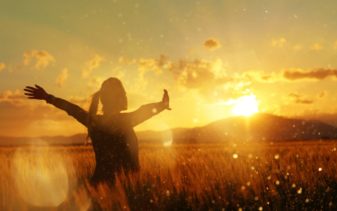 how to hear your inner voice again: A women standing in a field with arms stretched during golden hour